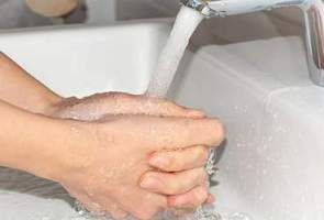 Pessoa lavando as mãos na água de torneira