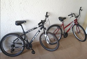 Foto de duas biciclestas encostadas na parede sendo uma preta e outra vermelha