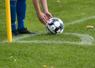 Imagem de um jogador preparando a bola para a cobran&ccedil;a de escanteio.