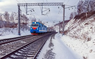 Foto de um trem passando pela ferrovia transiberiana com cen&aacute;rio de vegeta&ccedil;&atilde;o coberta por neve