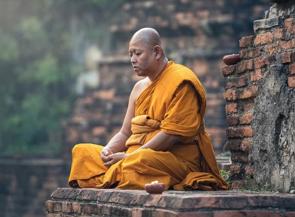 Monge budista sentado e fazendo uma meditação