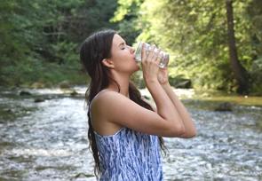 Foto de uma mulher bebendo água na natureza