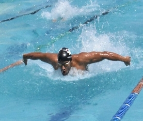 Homem nadando numa piscina no estilo borboleta
