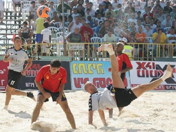 Foto de jogadores participando de uma partida de futebol de areia