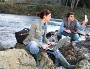 Foto de dois pesquisadores de Hidrogeografia nas margens de um rio