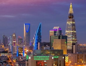 Foto noturna da cidade de Riad mostrando prédios modernos iluminados