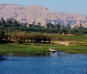 Foto do rio Nilo com árvores na margem e montanha ao fundo